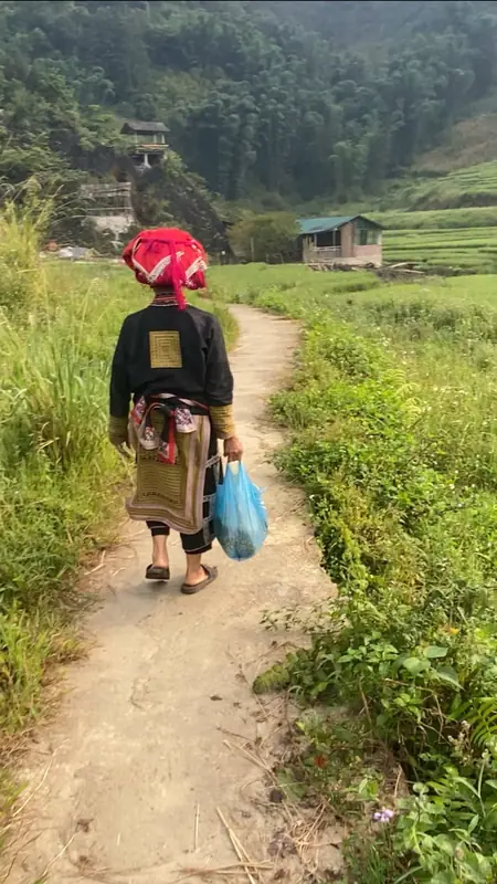 Bà Dao Đỏ đi trên đường mòn ra khỏi bản